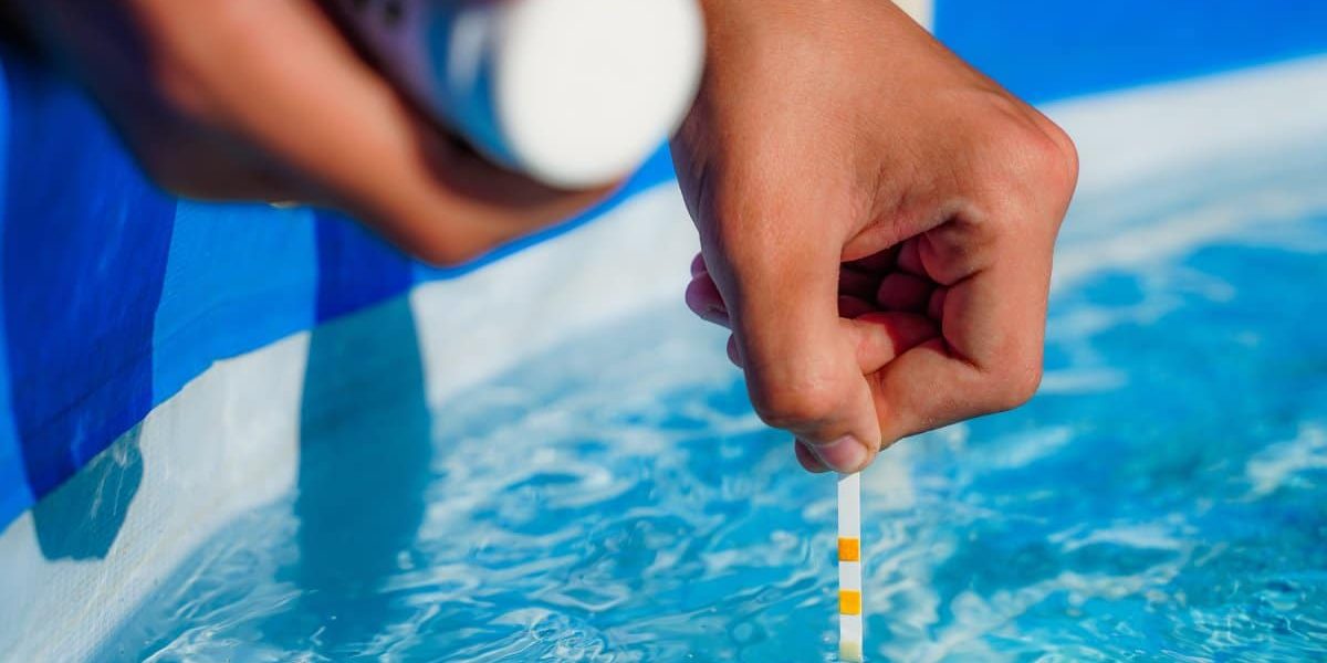 GulfCoastPoolConsultingConstruction-398295-Pool-Chlorine-Level-blogbanner1 An individual uses a white pH strip with yellow markings to test a pool's chlorine level on a sunny day.